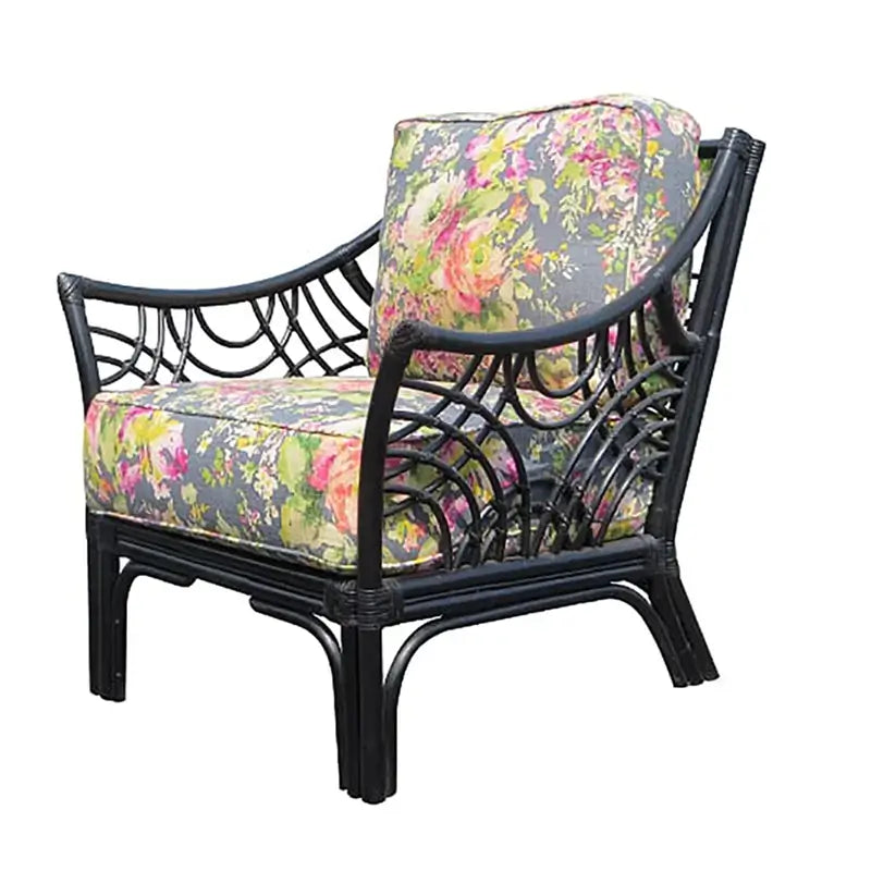 Black rattan lounge chair with arched spoke arms and gray cushions printed with pink roses, angled view