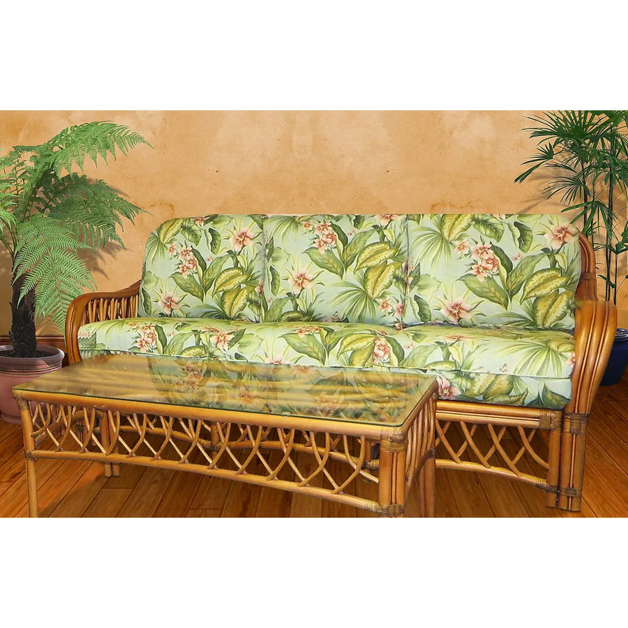 Montego Bay coffee table with a clear glass top in front of the matching sofa with light green tropical leaf cushions