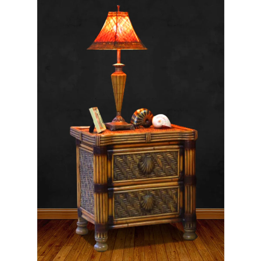 Brown rattan nightstand from Royal Palm in Antique Brownwash, styled with an amber lamp, seashells and a small frame