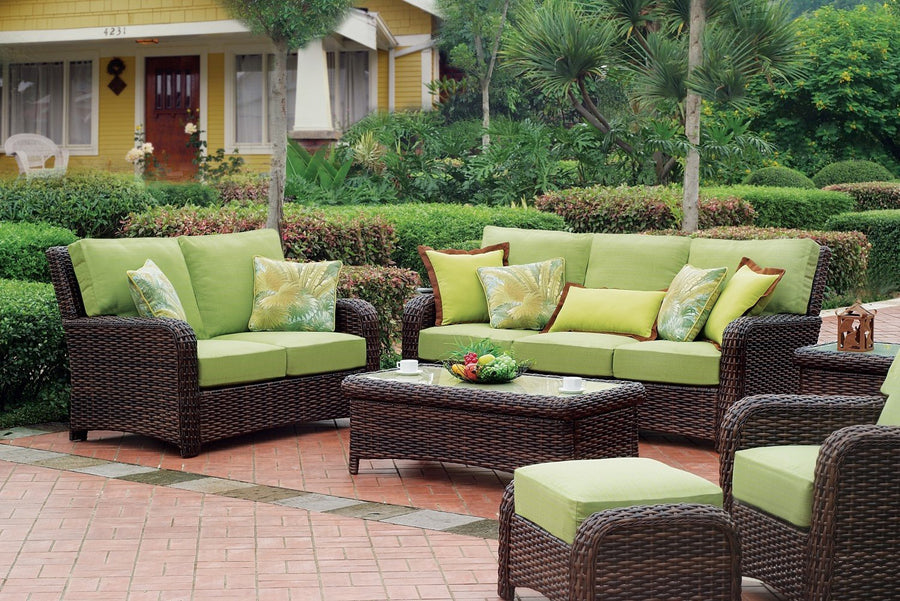 Tobacco St. Tropez sofa, loveseat, ottoman and chair with lime green cushions around the coffee table outside a yellow house