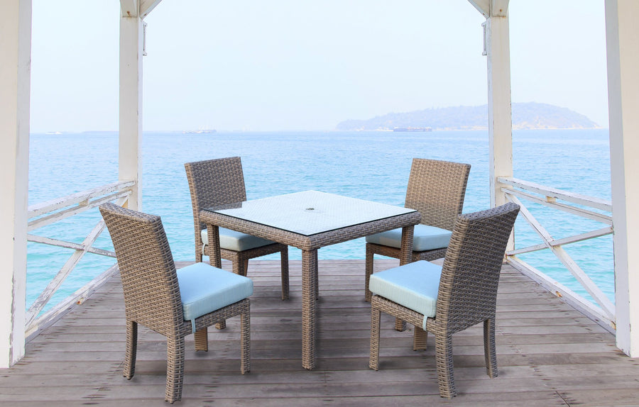 Stone St. Tropez square table and side chairs with pale blue cushions on a pier over the sea