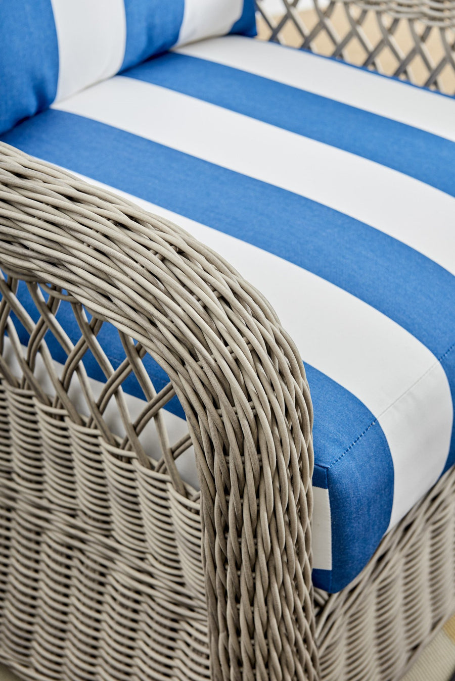 Driftwood wicker arm on an Arcadia piece, shown up close with a blue and white striped cushion