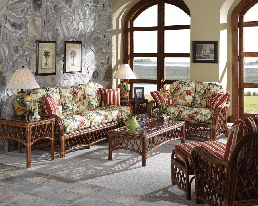 Antigua seating group with floral cushions, a red striped armchair and ottoman, and a stone wall behind