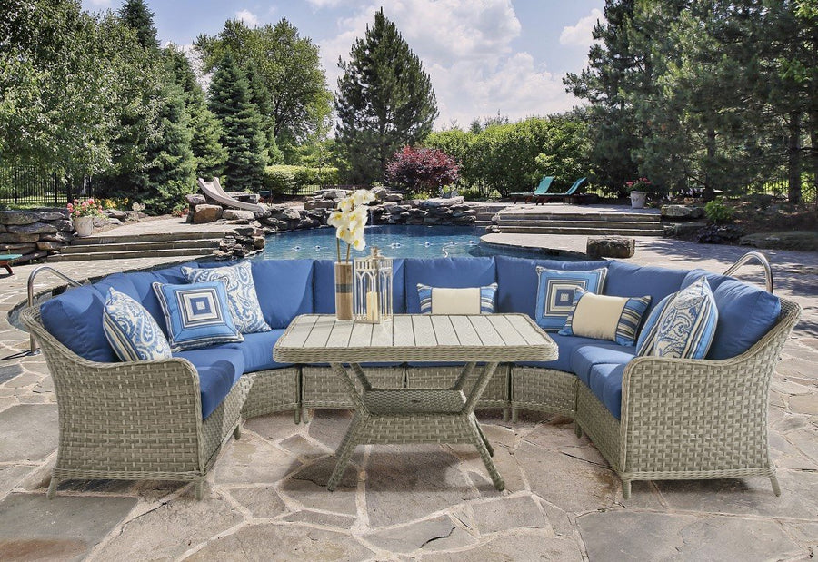 Mayfair sectional in Pebble with blue cushions and a slatted-top table beside a pool