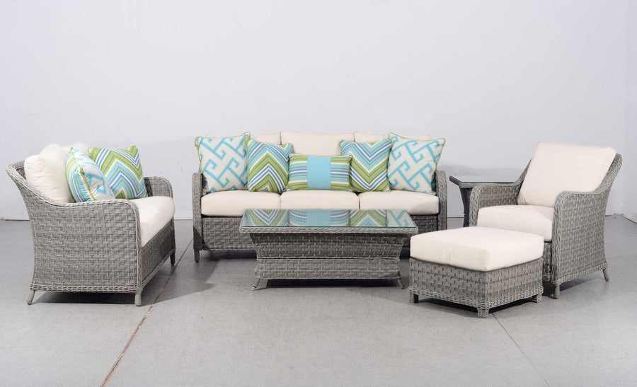 Mayfair seating group in Pebble wicker with chevron pillows, an ottoman and glass top tables