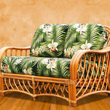 Montego Bay loveseat in cinnamon rattan with green palm leaf and white orchid cushions, tan wall