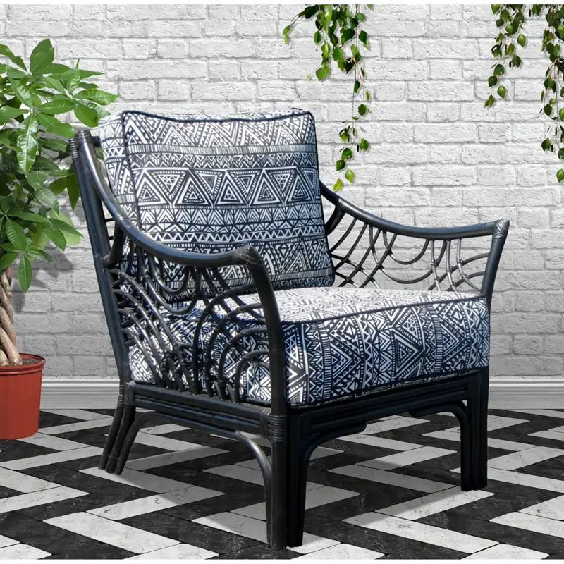 Bali black rattan accent chair with navy and white geometric cushions beside a potted plant