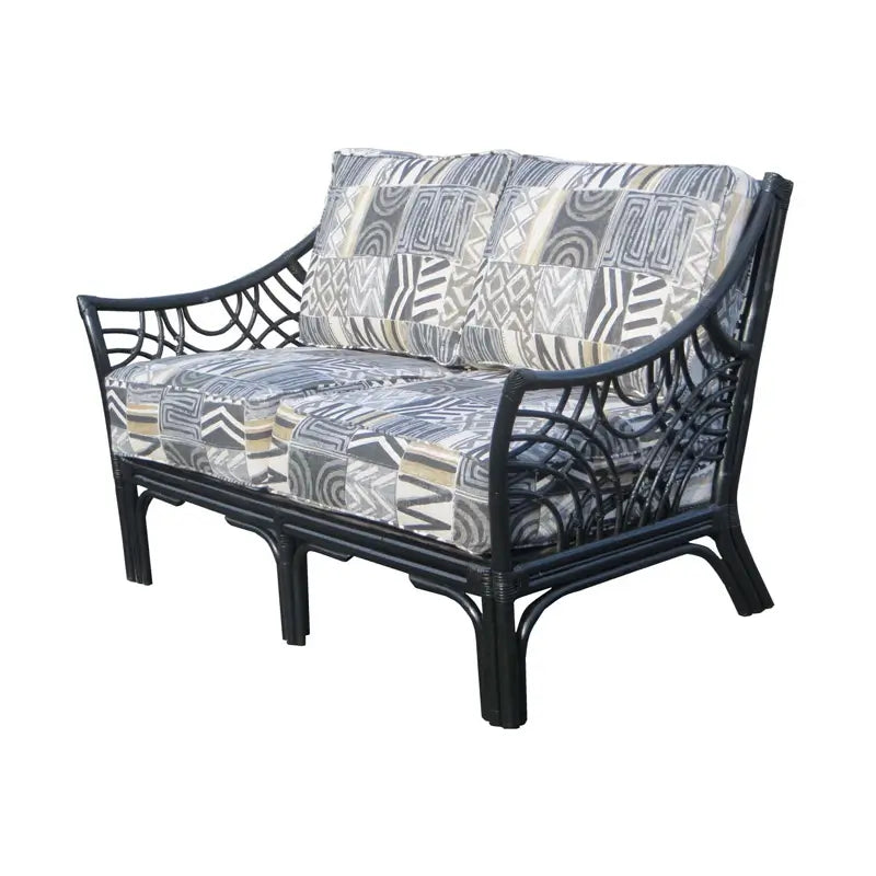 Black rattan Bali loveseat on a white background, its patchwork print cushions framed by the flared arms and arcs