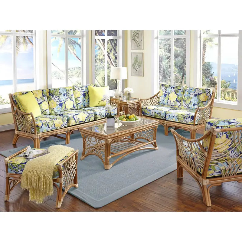 Bali sofa in Natural with blue and yellow floral cushions, beside a matching loveseat and glass coffee table in a sunroom