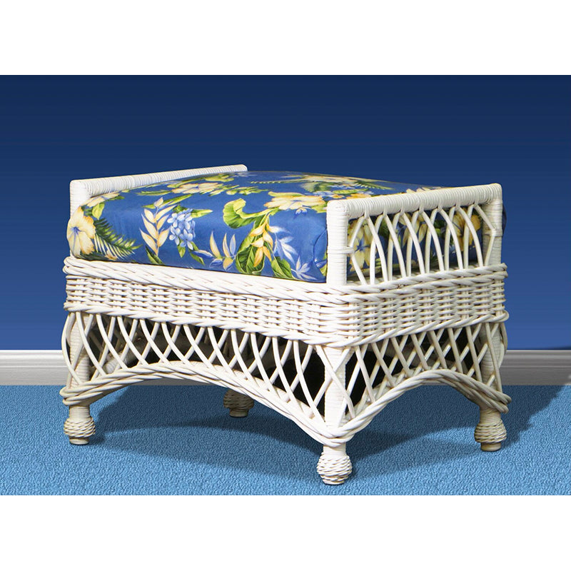White wicker Bar Harbor ottoman from the front, with a blue tropical floral cushion and a diamond lattice skirt