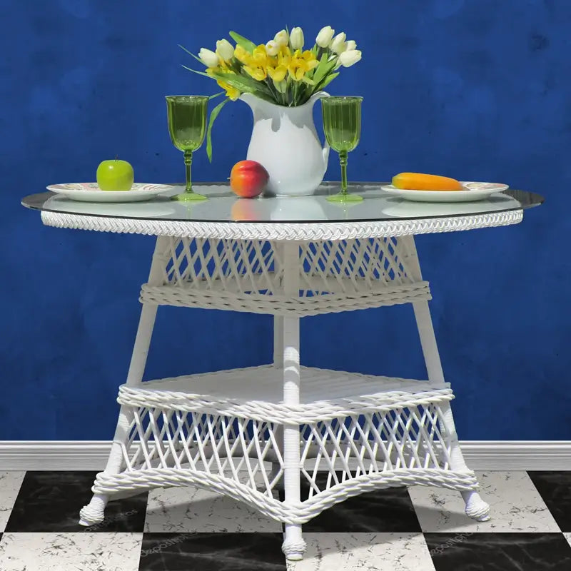 Close look at the round Bar Harbor table in white, its glass top resting on a woven wicker lower shelf