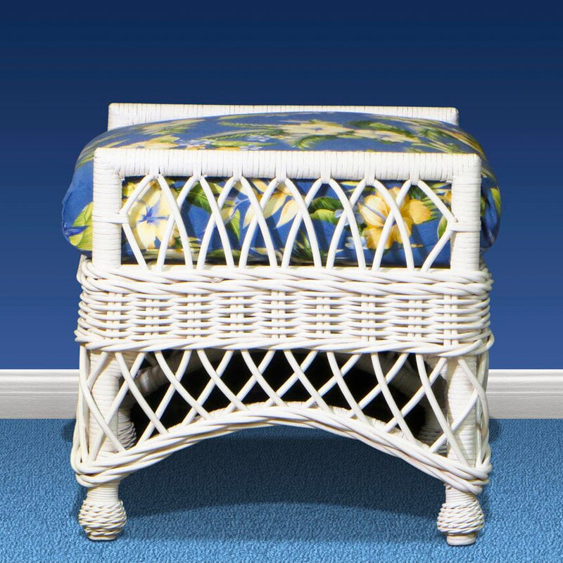White wicker Bar Harbor ottoman from the front, with a blue tropical floral cushion and a diamond lattice skirt