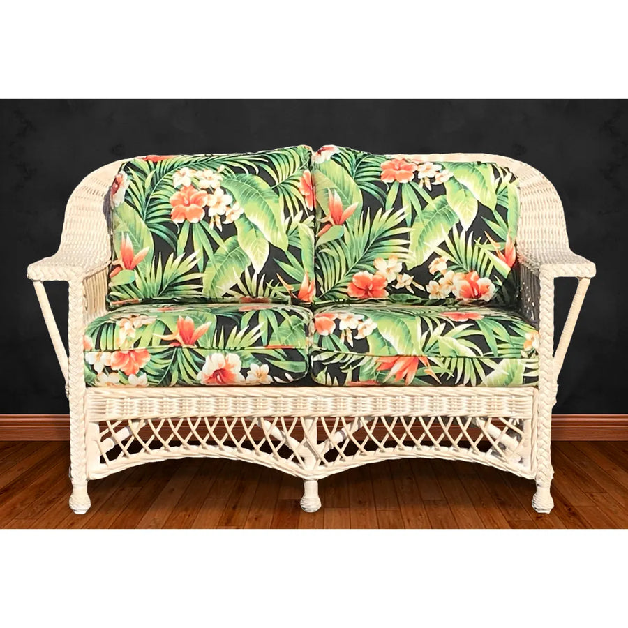 Whitewash wicker furniture from Bar Harbor: the loveseat with black tropical cushions printed with orange blooms, on a wood floor