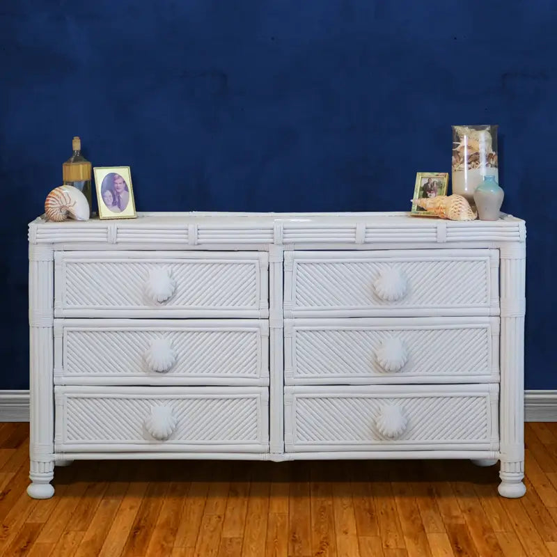 Coastal white dresser, front view, with diagonal-woven drawer fronts, seashell pulls and bun feet on a navy blue wall