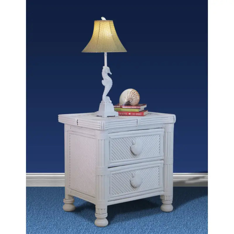 White coastal night stand against a navy wall, topped with a seahorse lamp, a nautilus shell and stacked books