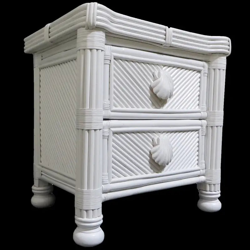 White two-drawer night stand on a black background, showing wrapped corner poles, shell pulls and bun feet