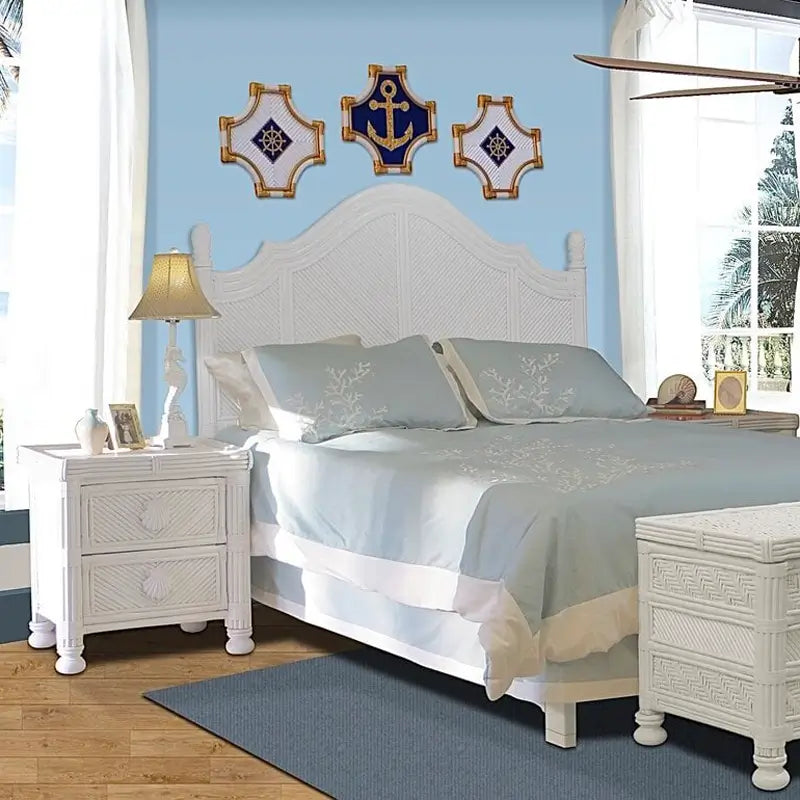 White wicker headboard with an arched top, pineapple finials and four diagonal-woven panels on a blue wall