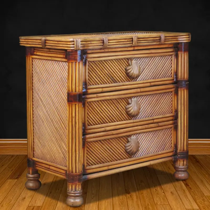Antique brownwash rattan dresser at an angle, showing the woven side panel, rattan pole frame and bun feet