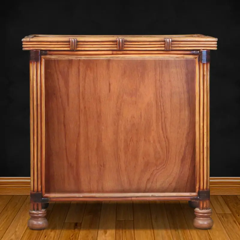 Back of the antique brownwash rattan dresser, showing a wood-grain back panel framed by rattan poles