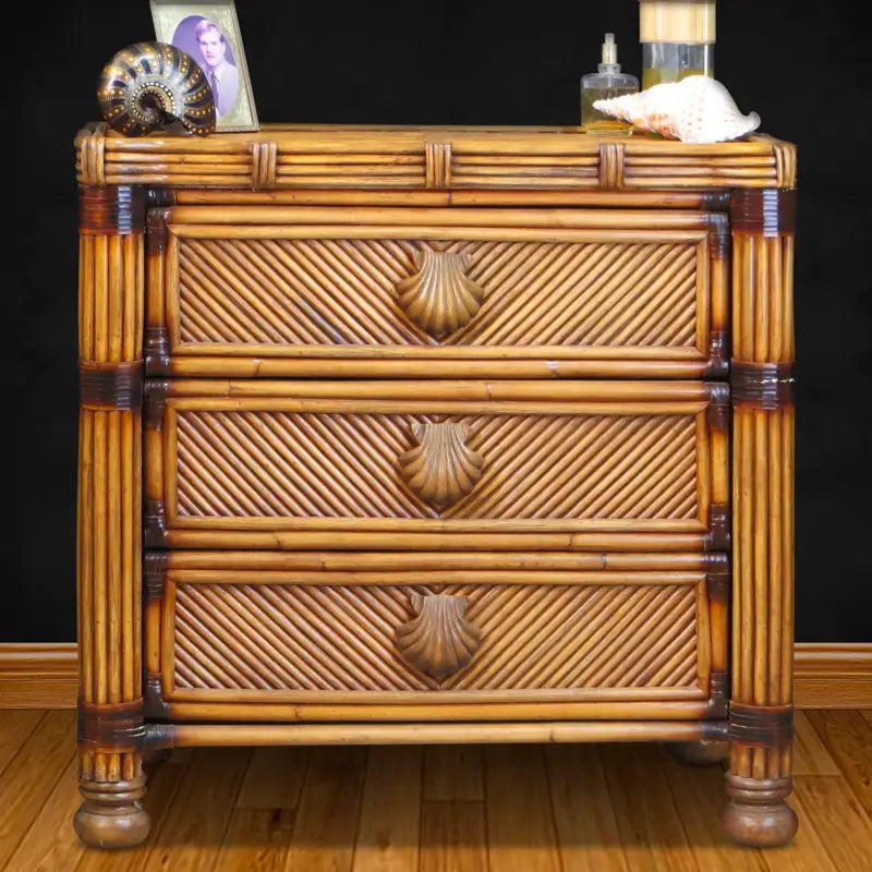 Antique brownwash rattan dresser with seashell pulls, styled with shells and a picture frame against a dark wall