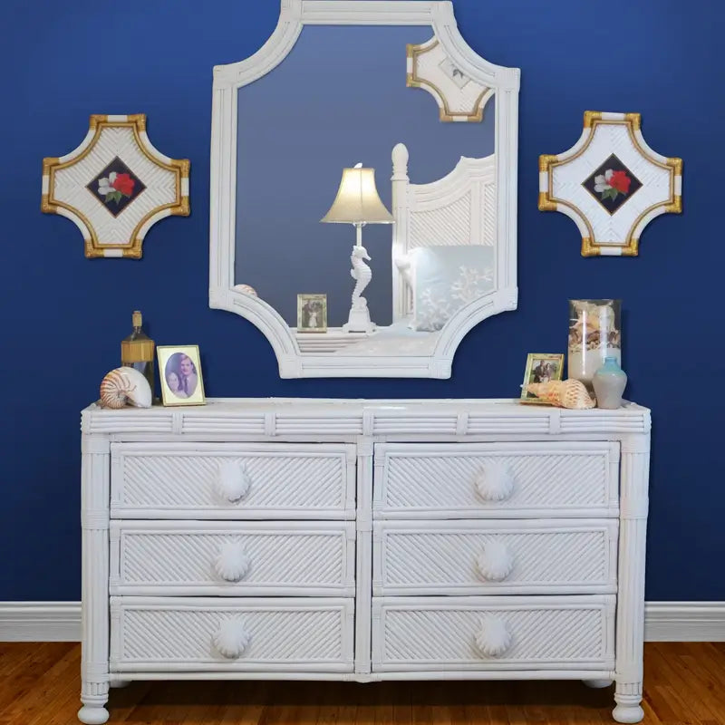 Coastal white dresser, front view, with diagonal-woven drawer fronts, seashell pulls and bun feet on a navy blue wall
