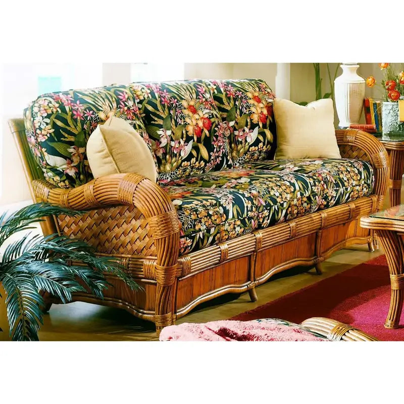 Kingston Reef wicker couch in cinnamon with black tropical floral cushions, two cream pillows and rolled rattan arms