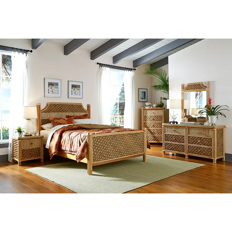 Rattan nightstand with two woven drawers beside a matching bed in a sunny bedroom, with a dresser, tall chest and mirror