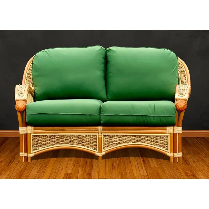 Spice Islands Seascape loveseat in natural rattan, facing forward, with carved shells on the arm fronts and green cushions