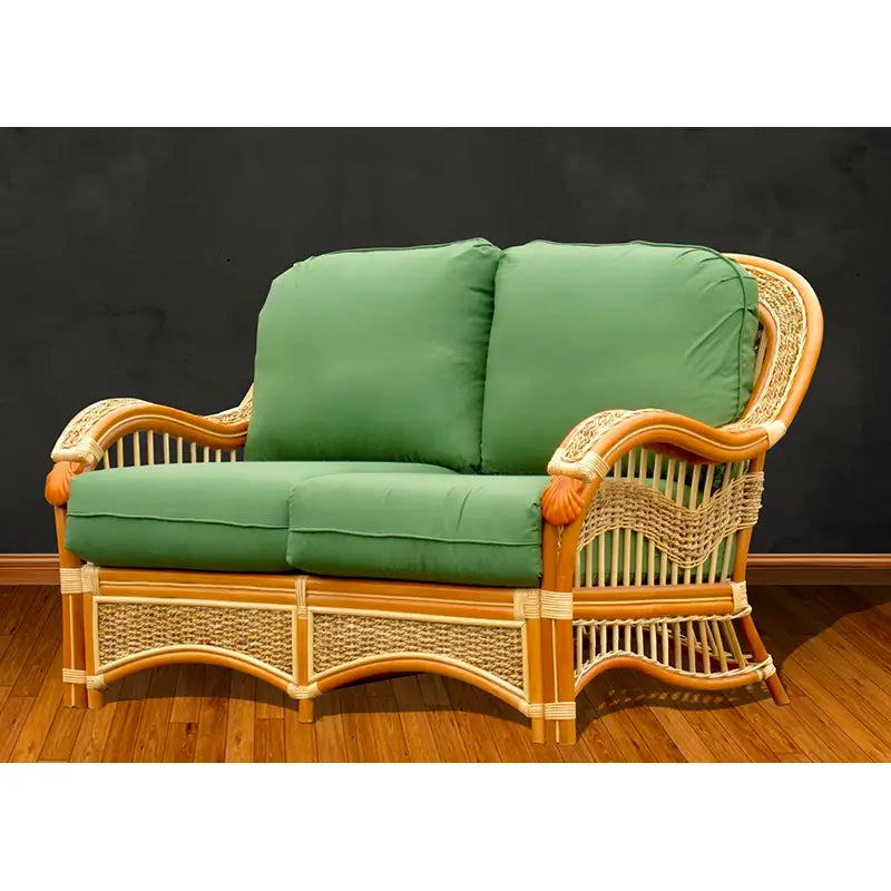 Spice Islands Seascape loveseat in natural rattan, facing forward, with carved shells on the arm fronts and green cushions