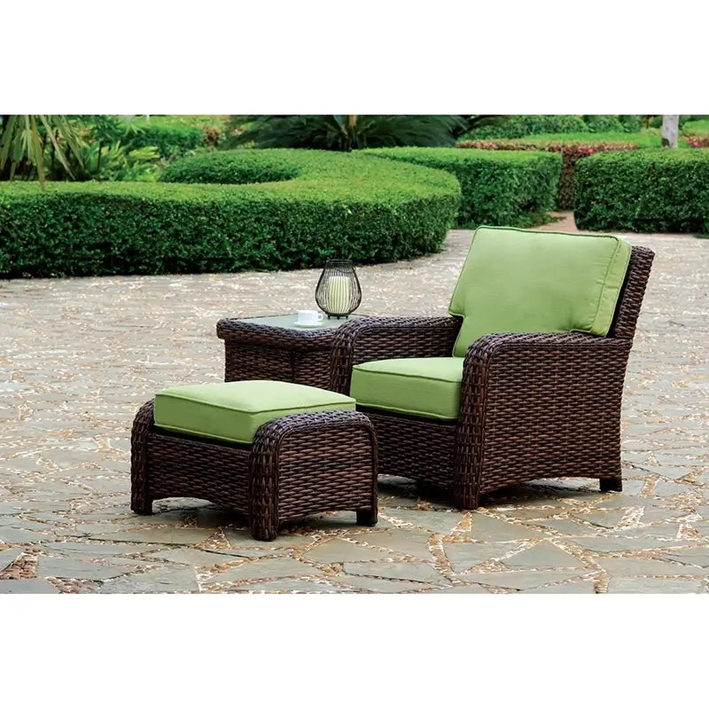South Sea Rattan St. Tropez armchair, ottoman, and side table in Tobacco finish with green cushions on outdoor patio