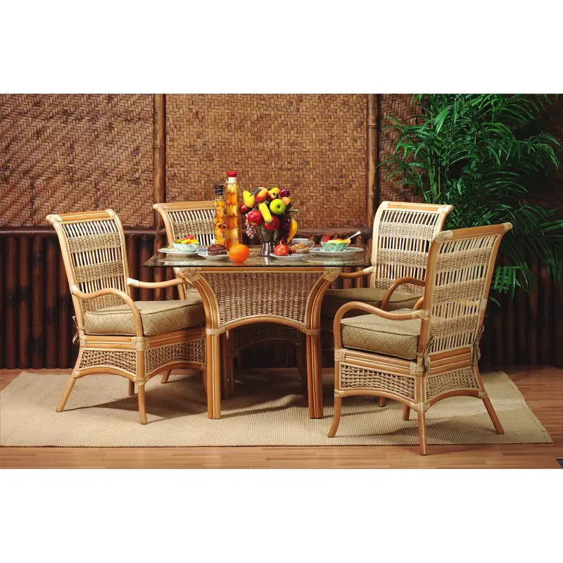 Natural rattan dining chair with curved arms, a woven high back and a green palm leaf print seat cushion