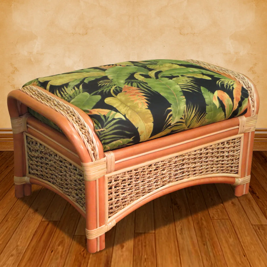 Spice Island rattan footrest in natural with a black tropical palm cushion against a tan wall