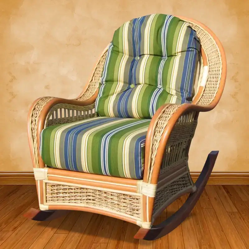 Wicker rocking chair in a natural finish with green, blue and cream striped cushions, on a wood floor by a tan wall