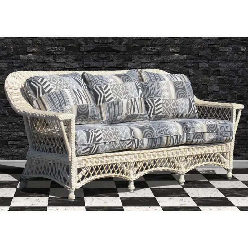 Whitewash Bar Harbor wicker sofa with gray geometric patchwork cushions, diamond lattice sides and a scalloped skirt