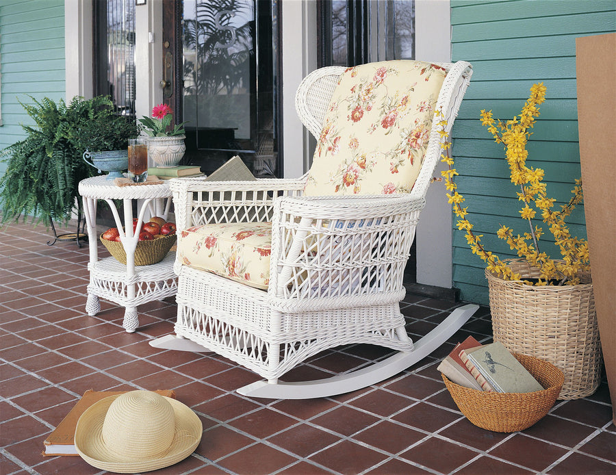 Concord rocker in White on a tiled porch with yellow floral cushions beside a round end table