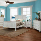 White distressed bedroom set from Monaco in a blue room, with the bed, chest, nightstand, dresser and mirror