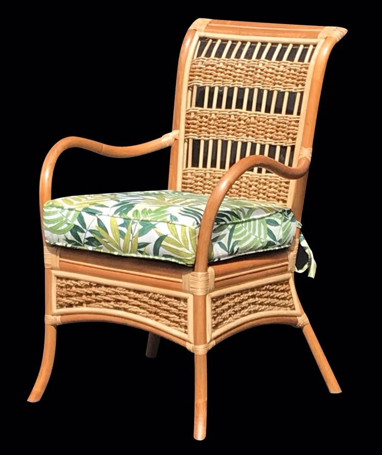 Spice Island dining arm chair in natural rattan with a green palm leaf seat cushion on a black background
